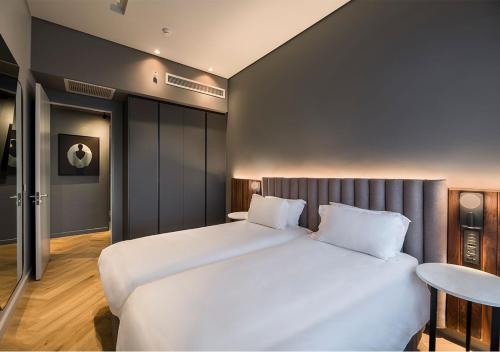 a bedroom with a large white bed and a table at The Rockefeller Hotel by NEWMARK in Cape Town