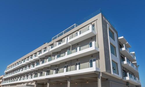 an apartment building with a blue sky in the background at Kos Divine Hotel & Suites in Kos