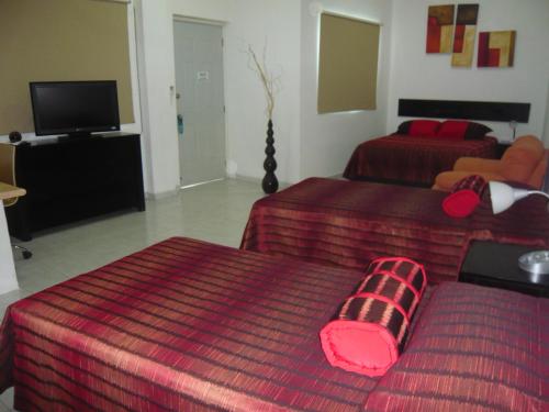 a hotel room with two beds and a flat screen tv at Aparthotel Siete 32 in Mérida