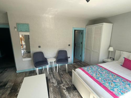 a bedroom with a bed and two chairs and a table at Villa Oliva Butik Hotel in Bodrum City