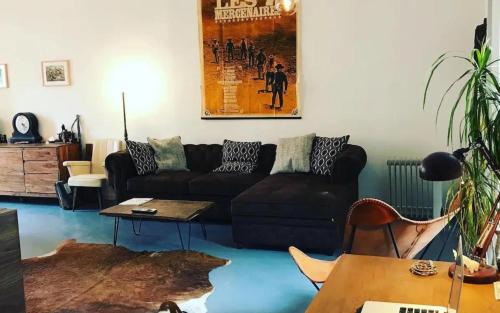 un salon avec un canapé noir et une table dans l'établissement Appartement chaleureux et atypique avec jardin à Marseille by Weekome, à Marseille