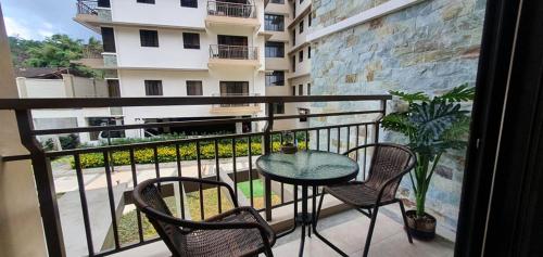 a balcony with a table and two chairs and a building at JCGA Apartments@Bristle Ridge Condominium in Baguio