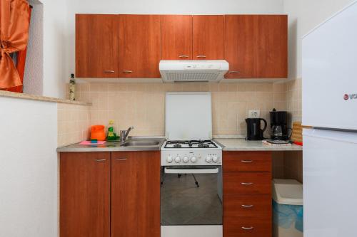 a kitchen with wooden cabinets and a stove top oven at MIMA house with apartments in Savudrija