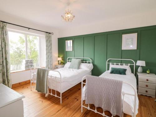 a green bedroom with two beds and a window at Lough View Cottage in Carrigart