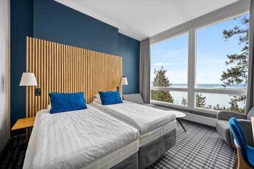 a bedroom with a large bed with blue walls and windows at Break Sokos Hotel Koli in Kolinkylä