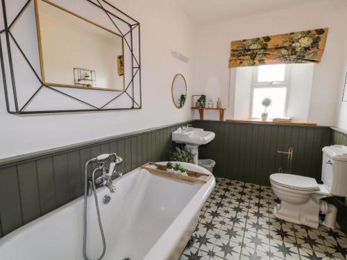 a bathroom with a tub and a toilet and a mirror at Lough View Cottage in Carrigart