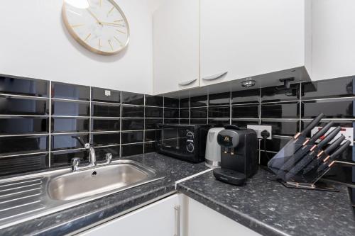 een keuken met een wastafel en een klok aan de muur bij King's Cross Apartments in Londen
