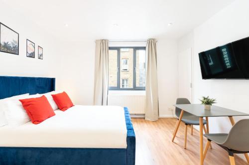 een slaapkamer met een wit bed met rode kussens en een tafel bij King's Cross Apartments in Londen