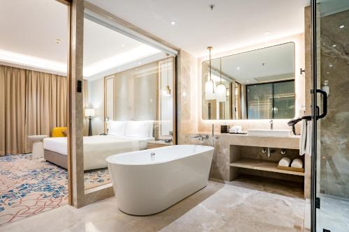 a bathroom with a tub and a bedroom with a bed at Holiday Inn Lucknow Airport by IHG in Lucknow