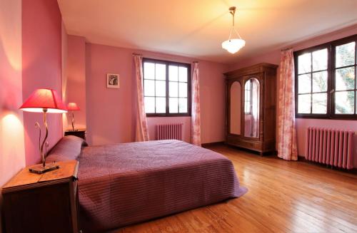 una camera da letto con pareti rosa, un letto e una lampada di Coumassous a Arricau-Bordes