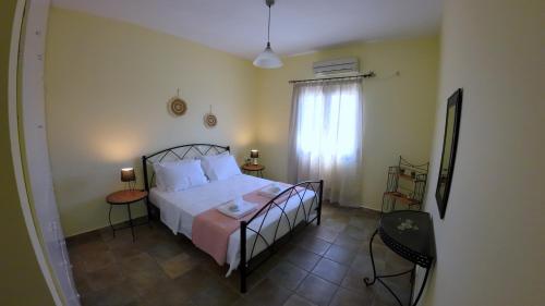 a bedroom with a bed and two tables and a window at Ze Di Ma House in Kýthira