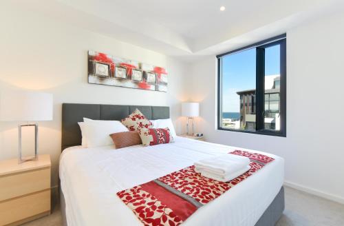 ein Schlafzimmer mit einem großen Bett und einem großen Fenster in der Unterkunft StayCentral - Spacious Seaviews Port Melbourne in Melbourne