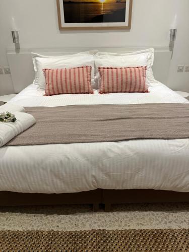 a large bed with white sheets and red pillows at The Beach House in Birżebbuġa