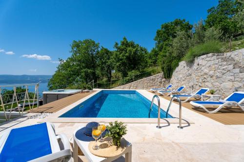 una piscina con sedie e tavolo e una piscina di Villa Maruncela with sea and island views, 5 bedrooms, private pool, gym a Lokva Rogoznica