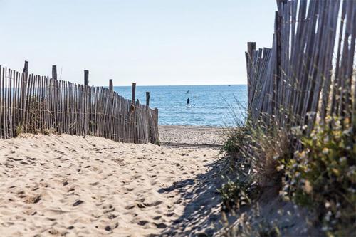 a fence on the beach with a person in the water at Mobil Home Camping Mar Estang 4* in Canet-en-Roussillon