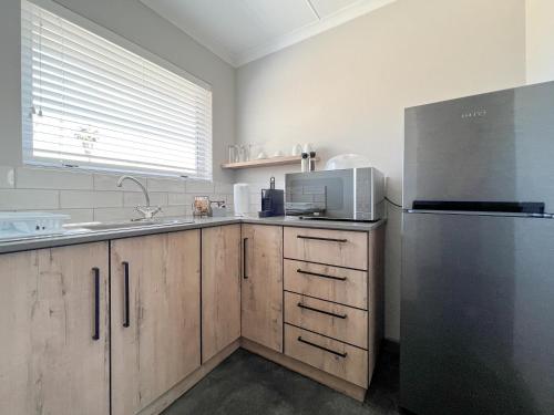 a kitchen with wooden cabinets and a refrigerator at The Featherbed - Oudtshoorn in Oudtshoorn