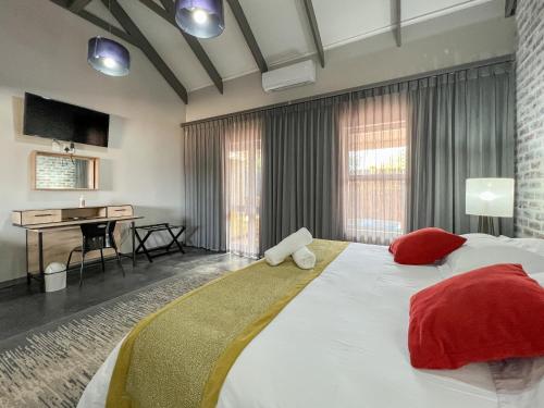 a bedroom with a large bed with red pillows and a desk at The Featherbed - Oudtshoorn in Oudtshoorn