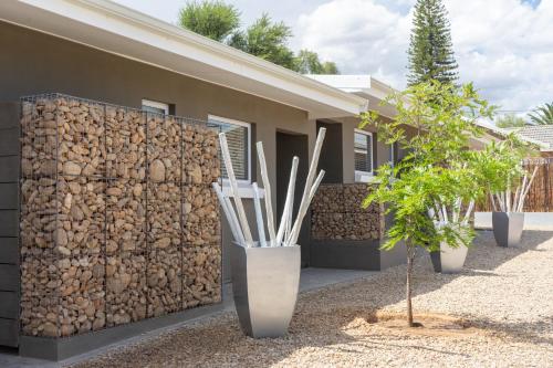 a wall of logs next to a house at The Featherbed - Oudtshoorn in Oudtshoorn
