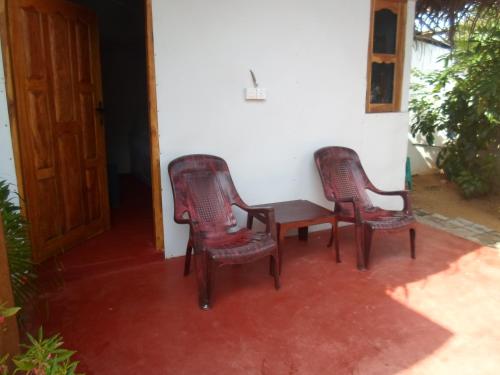 two chairs and a table on a porch at SURF & SAND Hotel Arugambay in Arugam Bay