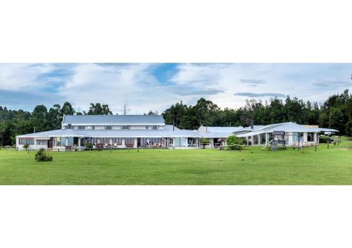 un grand bâtiment blanc avec une grande pelouse dans l'établissement Drakensberg Mountain Retreat, à Bergville