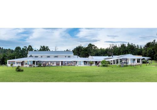 a large white building with a large grass field at Drakensberg Mountain Retreat in Bergville