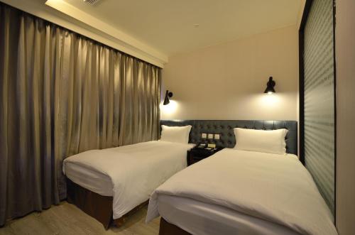 two beds in a hotel room with white sheets at Stay Hotel - Taichung Yizhong in Taichung