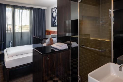 a bathroom with a glass shower and a sink at Hotel MANI by AMANO in Berlin