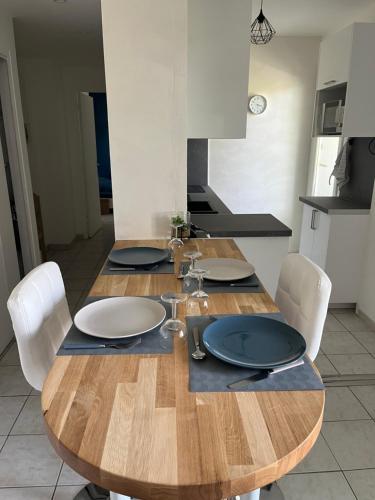 une table en bois dans une cuisine avec des chaises blanches et un plan de travail dans l'établissement Appartement cosy, à Six-Fours-les-Plages