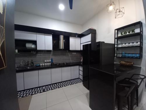 uma cozinha com armários a preto e branco e um frigorífico preto em RS Homestay em Sungai Petani
