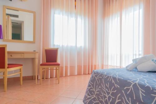 a bedroom with a bed and a desk and a mirror at Hotel America in Marina di Camerota