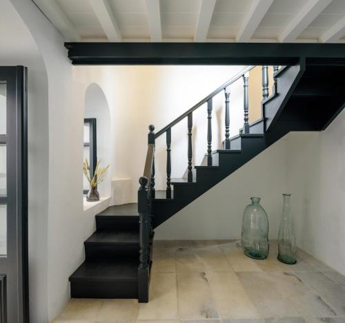 a staircase in a house with black stairs and white walls at Firalia, Casa in Rock Suites in Fira