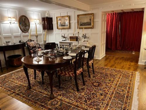 a dining room with a table and chairs on a rug at Whitehouse in Uplawmoor