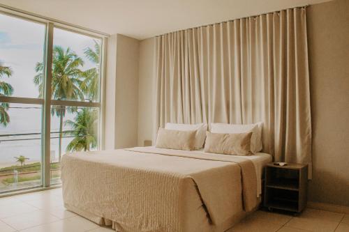 1 dormitorio con 1 cama grande y ventana grande en Nord Easy Green Sunset, en João Pessoa