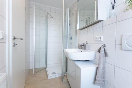 een witte badkamer met een wastafel en een douche bij City-House-Achern in Achern