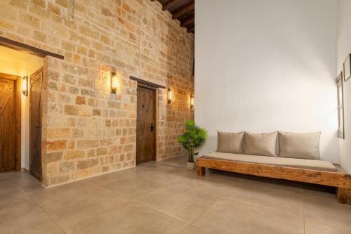 Ancient Knights Luxury Suites في بلدة رودس: أريكة في غرفة مع جدار من الطوب