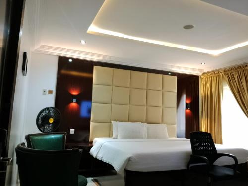 a hotel room with a bed and two chairs at Brickland Residence in Abuja