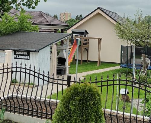 a fence in front of a house with a playground at Domček v záhrade in Liptovský Mikuláš