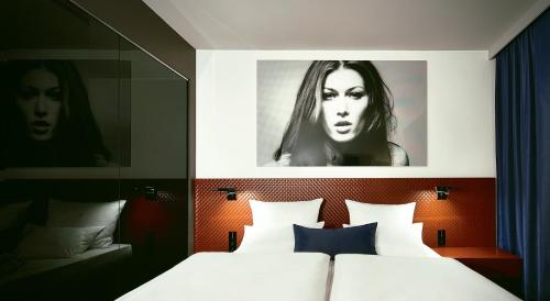 a bedroom with a bed with a picture on the wall at Hotel MANI by AMANO in Berlin