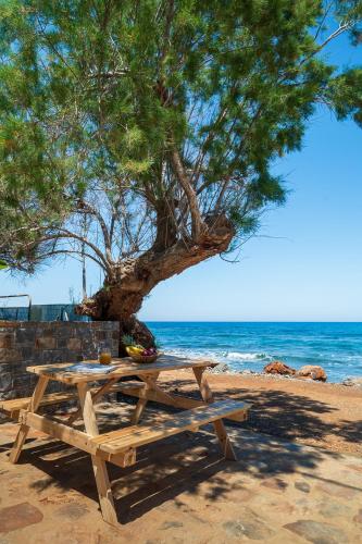 a picnic table under a tree on the beach at Milatos Seaside Suites in Milatos