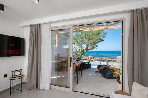 a living room with a sliding glass door to the ocean at Milatos Seaside Suites in Milatos