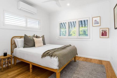 um quarto com uma cama com paredes e janelas brancas em Villa Wallah Luxury in Byron Bay em Byron Bay