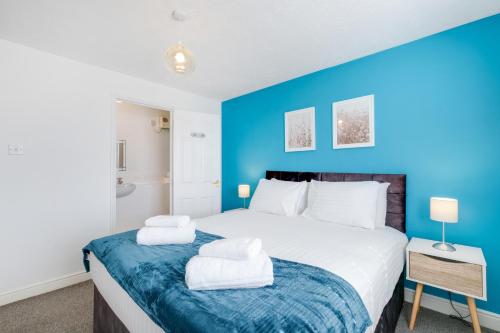 a bedroom with a large bed with a blue wall at 2 bed luxury apartment in Enfield