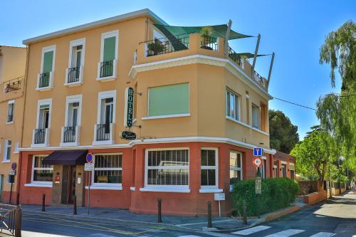 een geel en oranje gebouw op de hoek van een straat bij Hôtel Provençal in Bandol