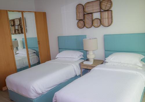 two beds in a hotel room with a mirror at Lagoona Beach Luxury Resort and Spa in Manama