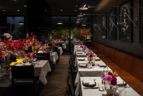 a row of tables in a restaurant with flowers at Hotel MANI by AMANO in Berlin
