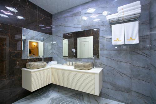 a bathroom with two sinks and two mirrors at Nohur Hotel Gabala in Gabala