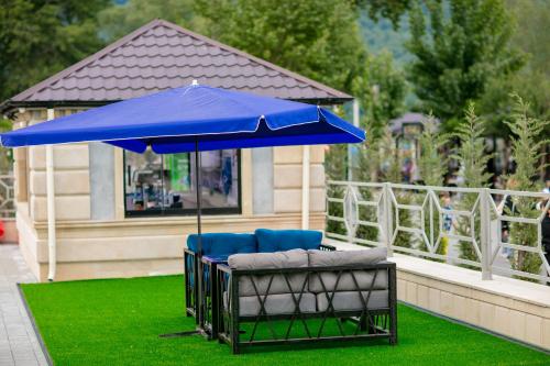 a blue umbrella and two chairs on a lawn at Nohur Hotel Gabala in Gabala