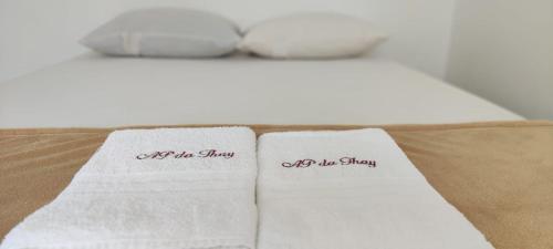 two white towels with the words off the shelf on a bed at Ap da Thay - Arretado in Campina Grande
