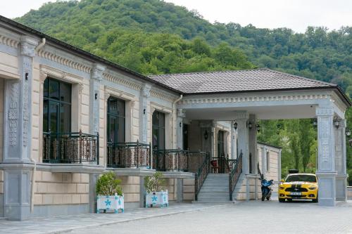 a yellow car parked in front of a building at Nohur Hotel Gabala in Gabala