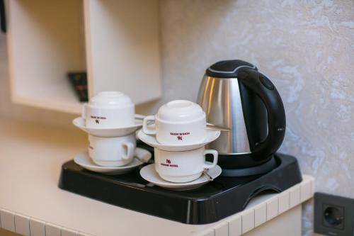 three coffee cups and a tea kettle on a counter at Nohur Hotel Gabala in Gabala